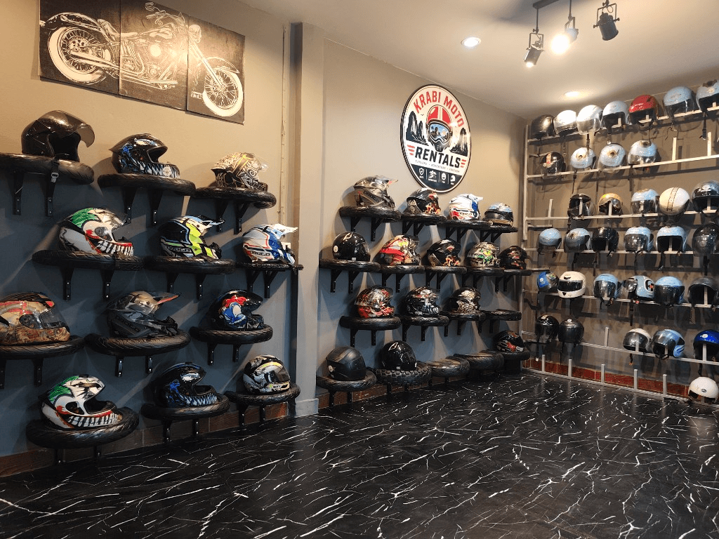 Helmet display wall with Krabi Moto Rentals branding in the shop