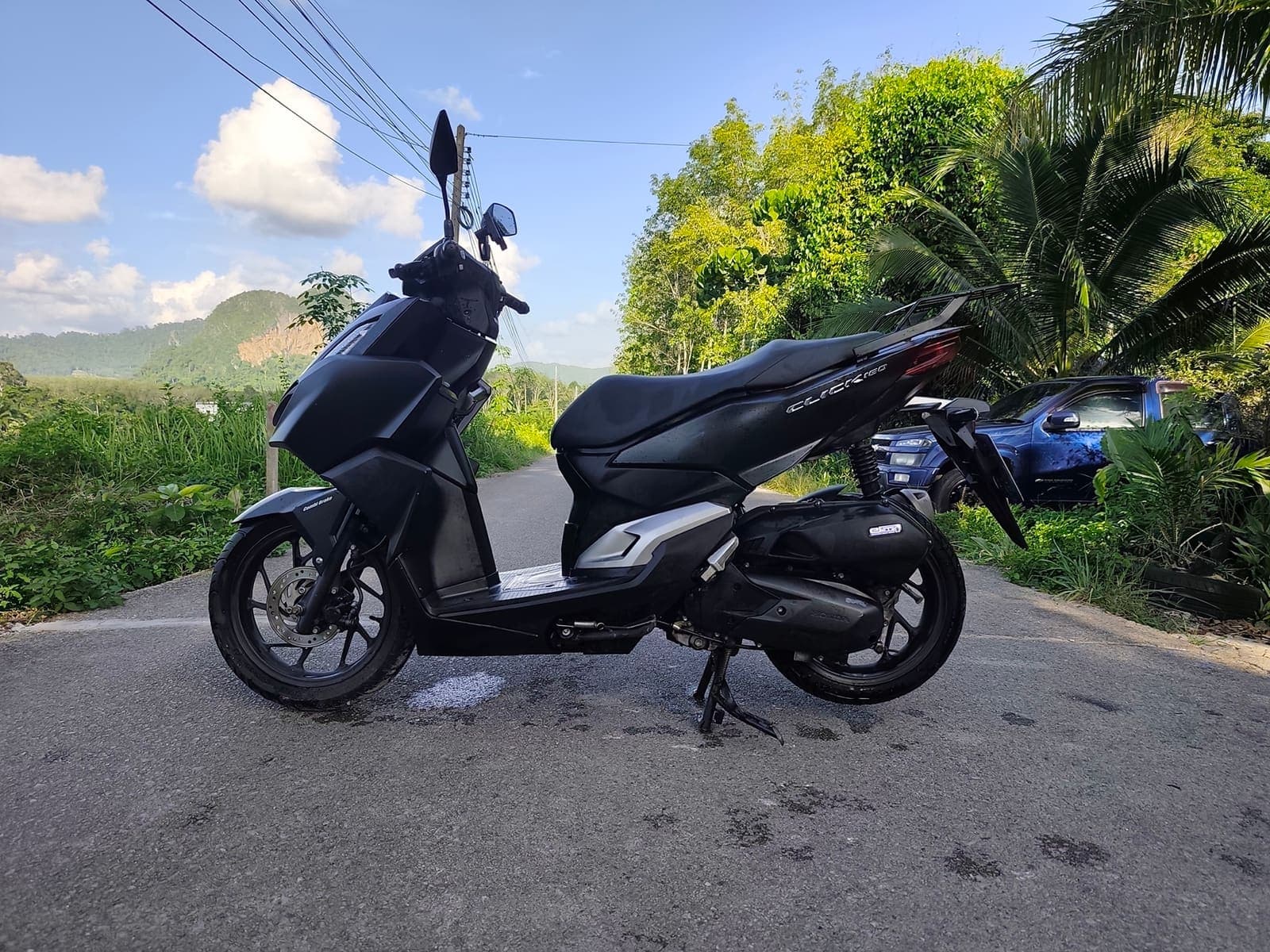 Honda Click 160 side profile on a scenic Krabi road