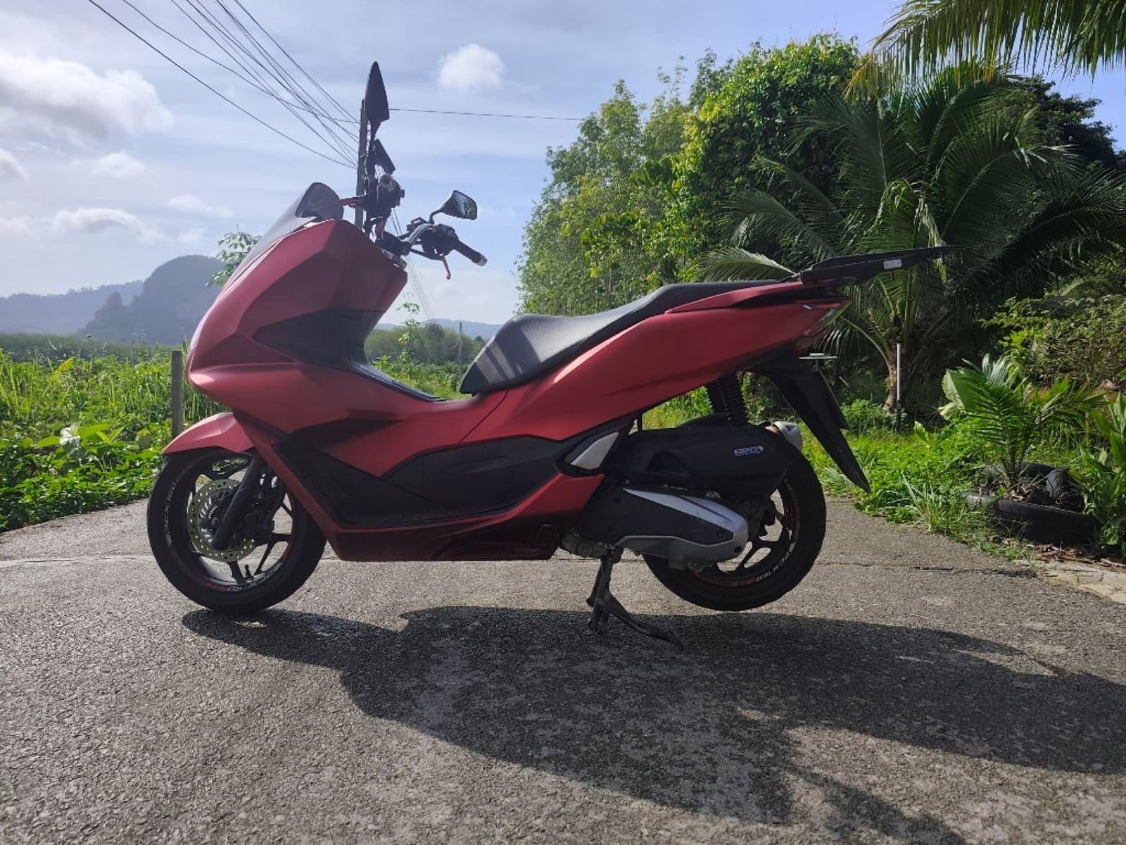 Honda PCX 160 side profile on a scenic Krabi road