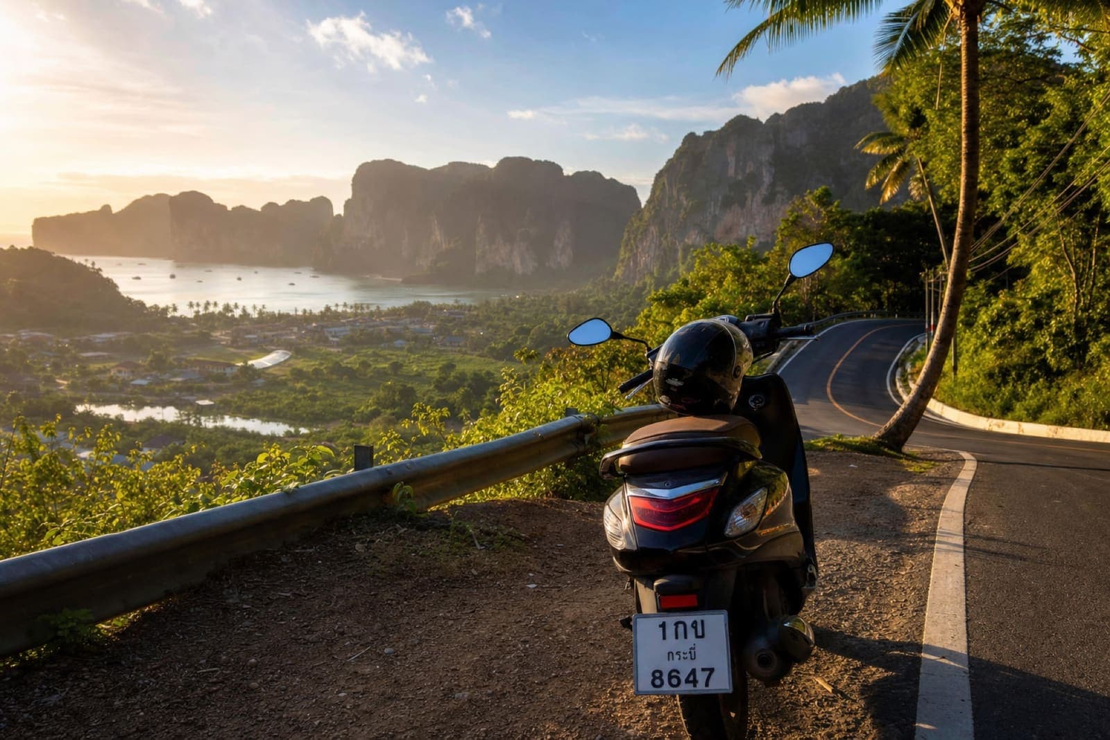 Scenic coastal road in Krabi Province with limestone cliffs and a rental scooter at a viewpoint