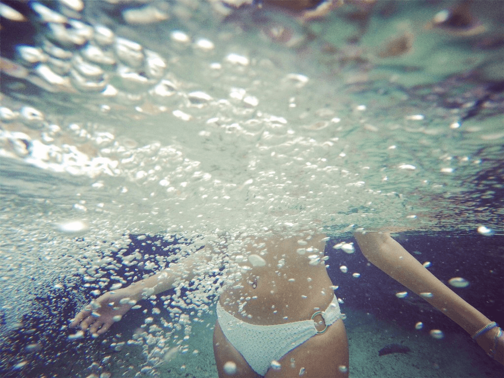 Swimmer in the bright clear water of Emerald Pool, Sa Morakot, Krabi