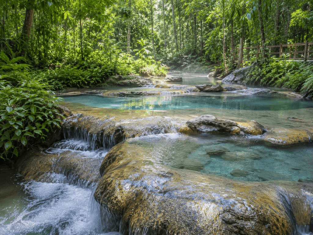Turquoise thermal pools and small cascades at Krabi Hot Springs among tropical forest