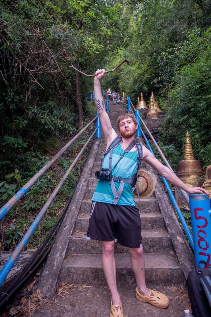 Steep staircase at Tiger Cave Temple through tropical forest with golden chedis alongside