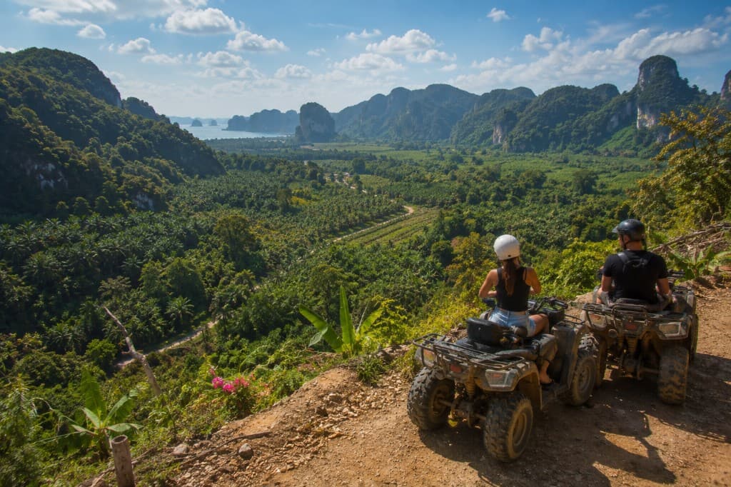 ATV riders at a nature viewpoint overlooking palm plantations and limestone mountains near Khao Thong, Krabi