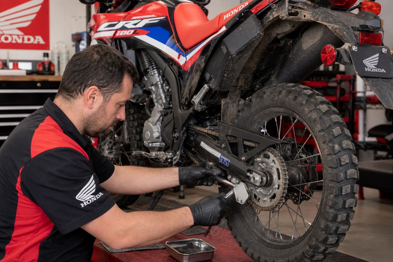 Mechanic servicing chain and sprocket on a Honda CRF adventure motorcycle