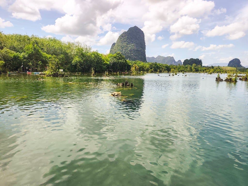 Kayaks on clear spring-fed water at Klong Root Clearwater Canal with limestone karst mountains, Krabi