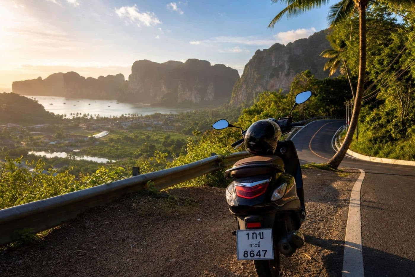 Scenic coastal road in Krabi Province with limestone cliffs and a rental scooter at a viewpoint
