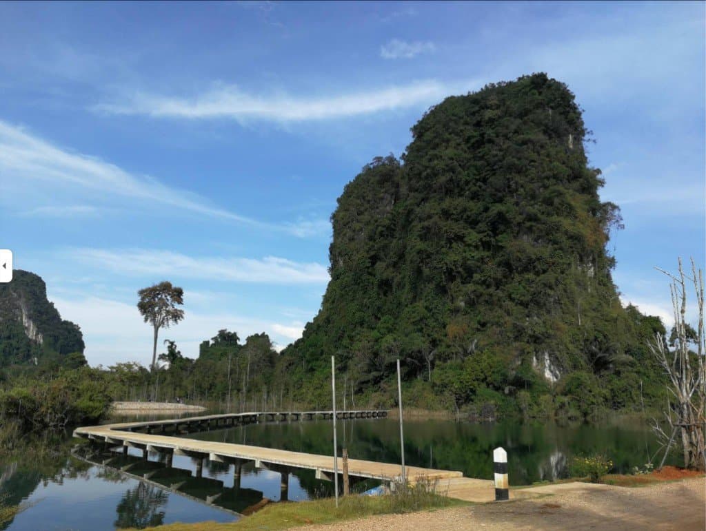 Khao Kham Dam with boardwalk across calm water and forested karst, Phang Nga