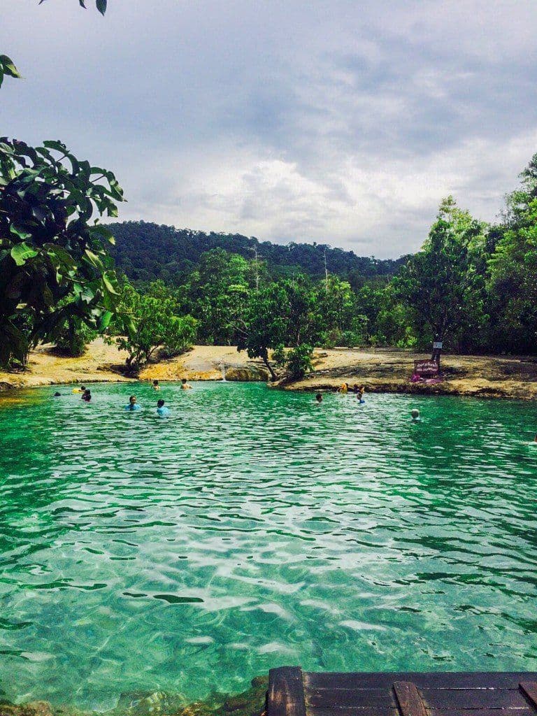 Portrait view of Emerald Pool (Sa Morakot) with jungle hills beyond the mineral-green water