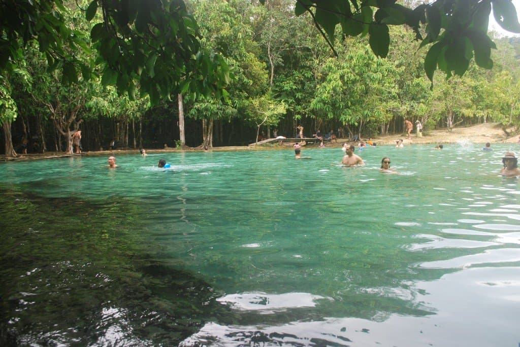 Wide view of Emerald Pool and swimmers in the rainforest sanctuary near Khlong Thom