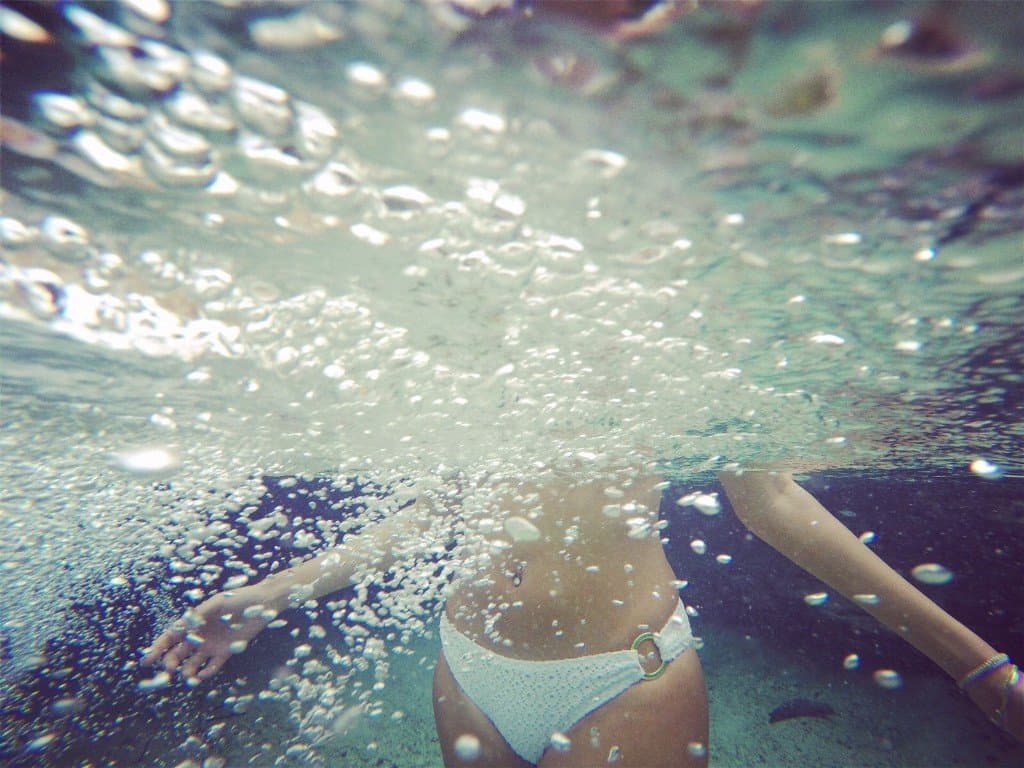 Swimmer in the bright clear water of Emerald Pool, Sa Morakot, Krabi