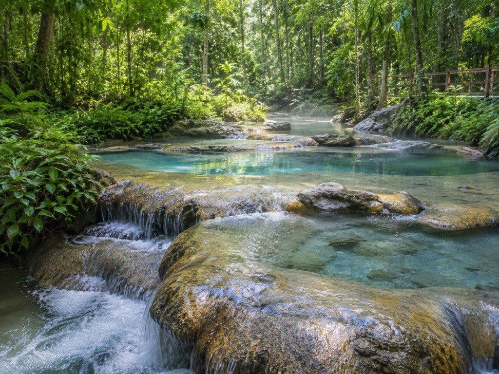 Turquoise thermal pools and small cascades at Krabi Hot Springs among tropical forest
