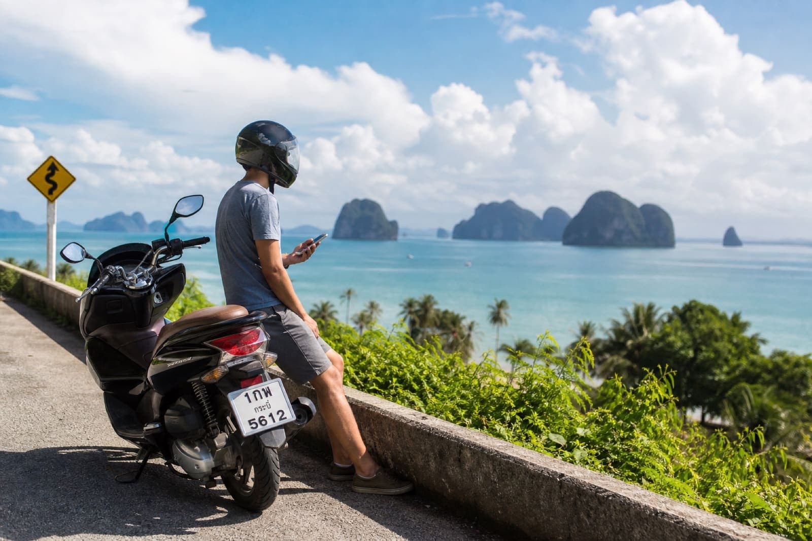 Scooter rider safely stopped on a scenic Krabi province road waiting for assistance