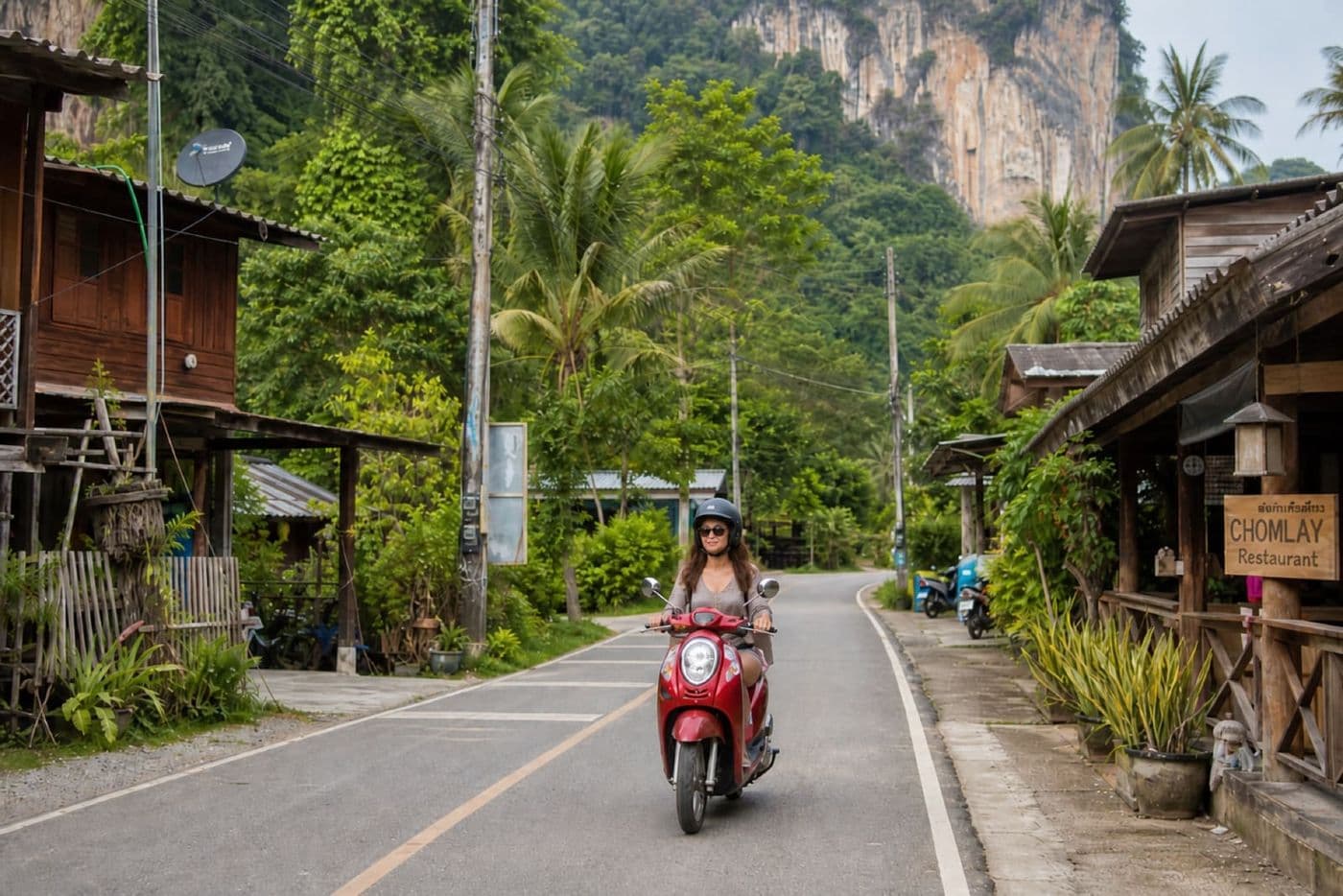 Scooter rider on a quiet road through a Thai village in Krabi Province
