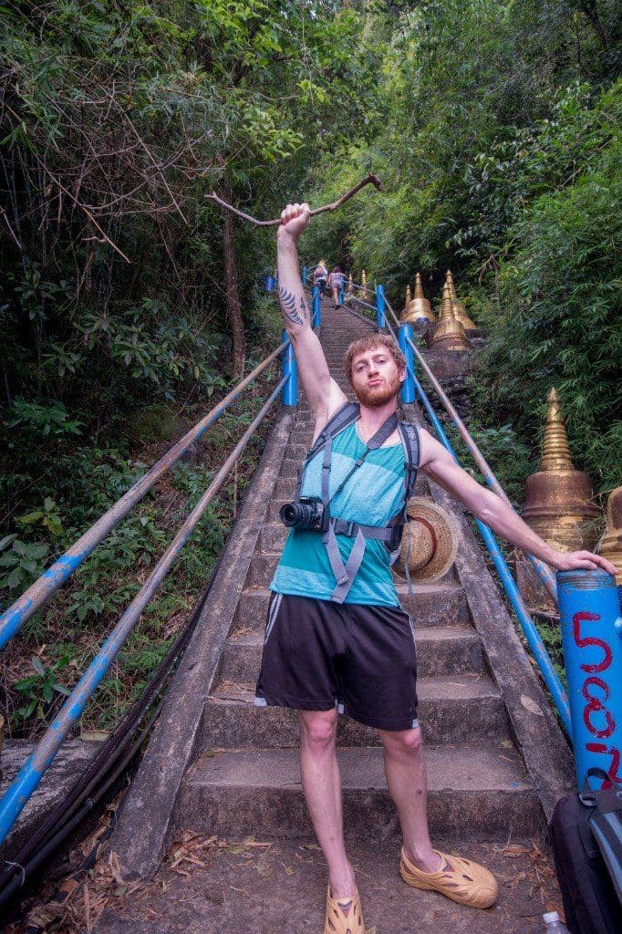 Steep staircase at Tiger Cave Temple through tropical forest with golden chedis alongside