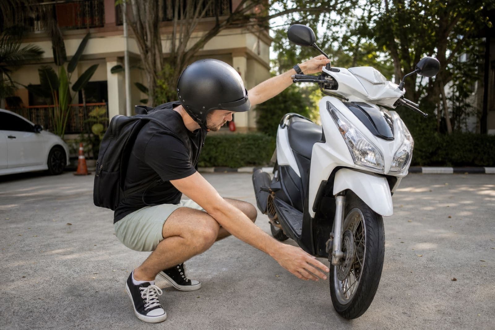 Rider checking scooter tyres and mirrors before setting off in Thailand